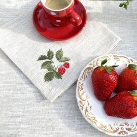 Handgefertigte Serviette Erdbeere aus naturfarbenem Leinen von Atelier Luhabru, botanisch bestickt, mit roter Tasse und frischen Erdbeeren